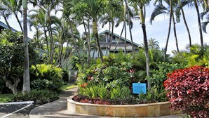 A private property with a landscaped garden, palm trees, and a building with a light blue roof. - Experience paradise at Kahana's beachfront 3-bedroom condo near Kaanapali Beach  (Lahaina)