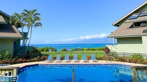 A pool area with lounge chairs and a view of the ocean. - Experience paradise at Kahana's beachfront 3-bedroom condo near Kaanapali Beach  (Lahaina)