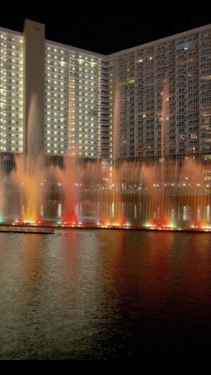 Experience the vibrant atmosphere of this high-rise building, featuring a stunning water feature with multiple fountains and a striking modern design.