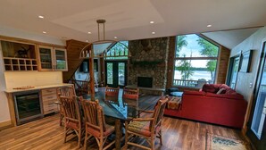 Un amplio salón con una mesa de comedor, sillas de madera, un sofá rojo y una chimenea de piedra.