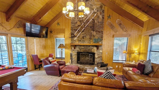 A cozy lodge interior with a stone fireplace, leather sofas, a pool table, and wooden walls. - Big 5Bd Pool Tbl, Hot Tub, Hiking, 10min to Beach (tahoe Vista)