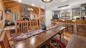 A spacious living area with a wooden dining table, a fireplace, and a kitchen area with modern appliances. - Big 5Bd Pool Tbl, Hot Tub, Hiking, 10min to Beach (tahoe Vista)
