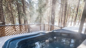 A hot tub surrounded by a wooden deck and snow-covered ground, with tall trees in the background. - Big 5Bd Pool Tbl, Hot Tub, Hiking, 10min to Beach (tahoe Vista)