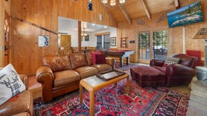 A wooden interior with a leather sofa, ottoman, and a pool table. - Big 5Bd Pool Tbl, Hot Tub, Hiking, 10min to Beach (tahoe Vista)