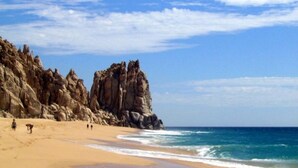 A beach with rocky cliffs and a clear sky. - ALL NEW remodeled condo! Ocean Front on Beach 2 Bd 2 Ba Upper Level (Cabo San Lucas)