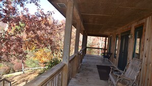 Een houten veranda met een balustrade, een bankje en een deur.