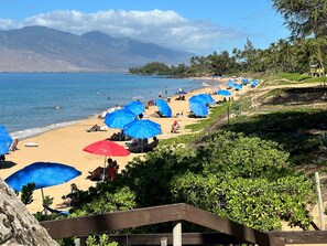A beach with umbrellas, people, and a mountainous backdrop. - PARADISE IS CALLING-Oceanview Family Size-Resort Zoned-King Beds-No Cleaning Fee (Kihei)