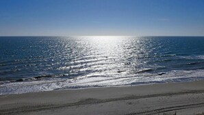 Une plage avec un ciel dégagé et la lumière du soleil se reflétant sur l’eau.