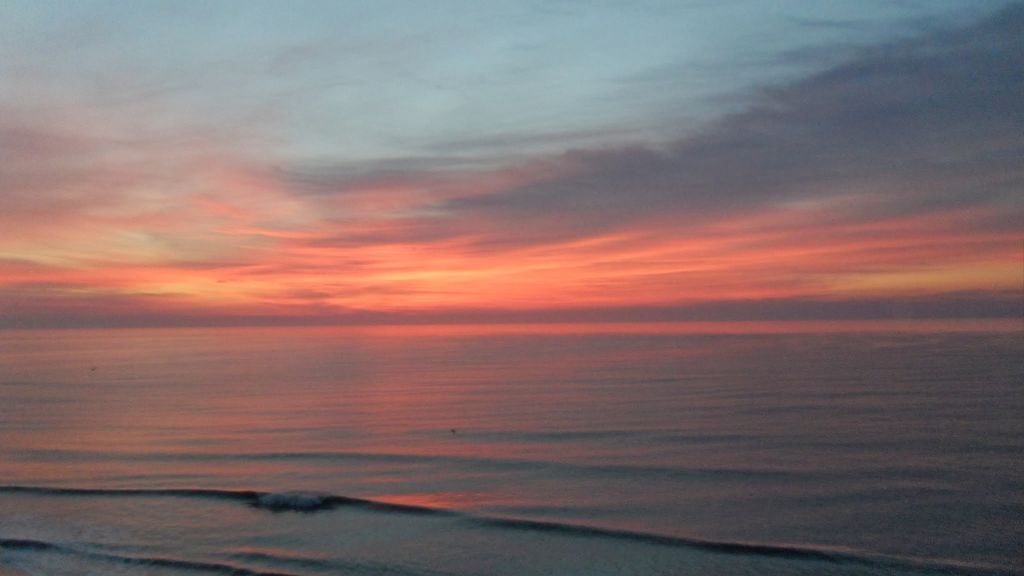 A sunset over a calm sea with a clear horizon.