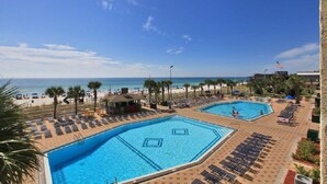 Ein Poolbereich mit zwei großen Pools, Liegestühlen und Blick auf den Strand.