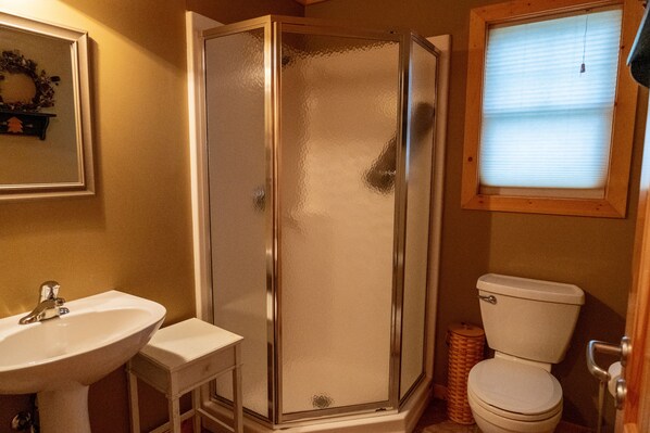 Une salle de bain avec une douche à parois de verre, un lavabo blanc et des toilettes.