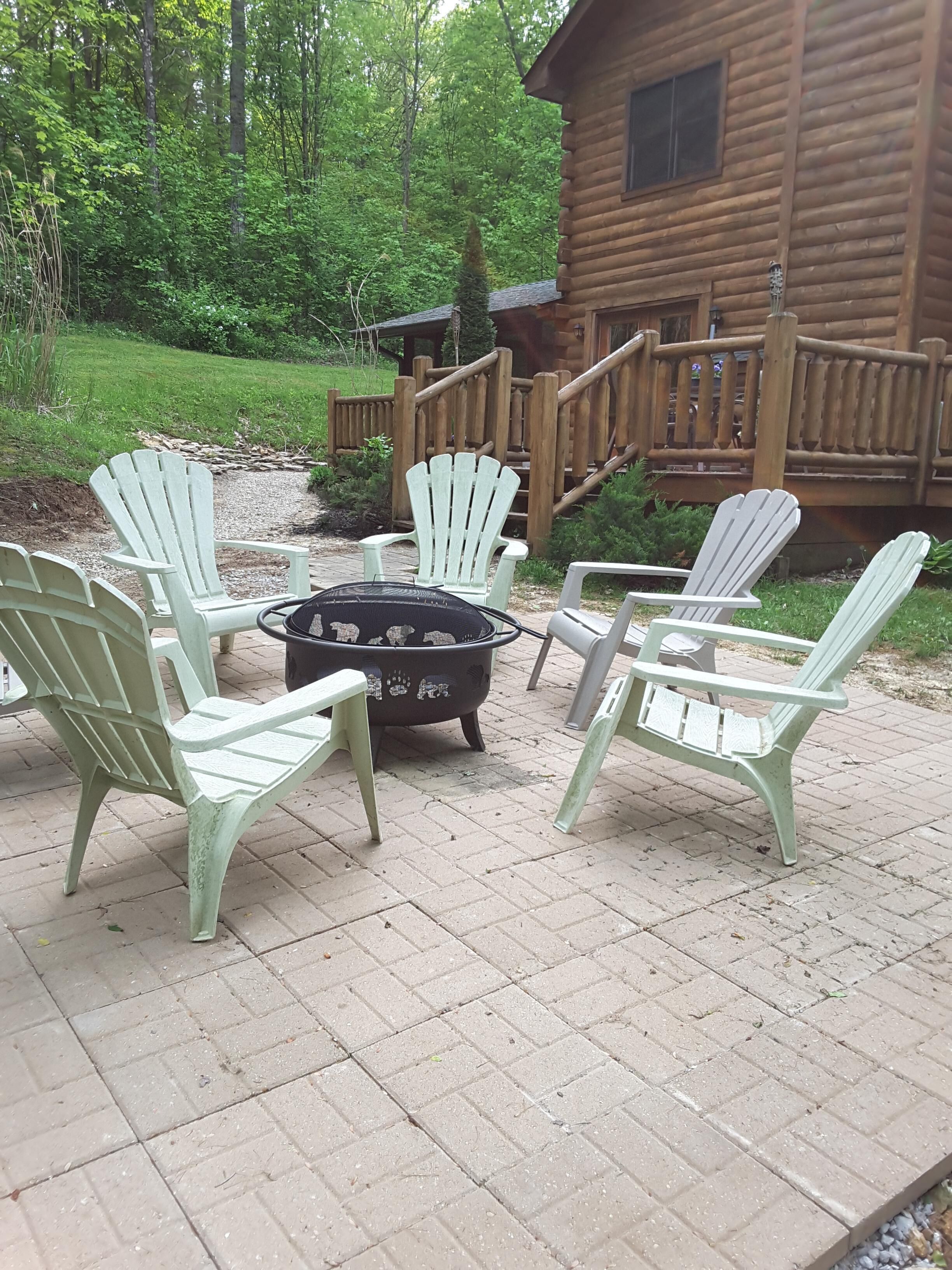 Een houten blokhut met een terras, omringd door groen.