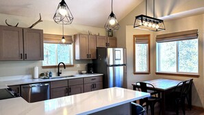 A modern kitchen with a central island, stainless steel appliances, and pendant lighting. - Cedar Barrel Sauna & Mtn Views - Pet-Friendly, 20 mi to Breckenridge (Fairplay)