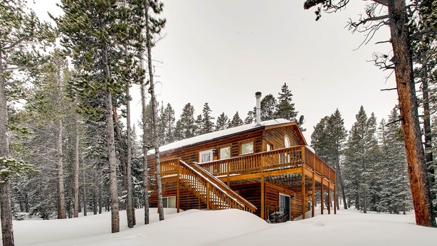 A log cabin with a wooden staircase leading to a deck, surrounded by snow-covered trees. - Cedar Barrel Sauna & Mtn Views - Pet-Friendly, 20 mi to Breckenridge (Fairplay)