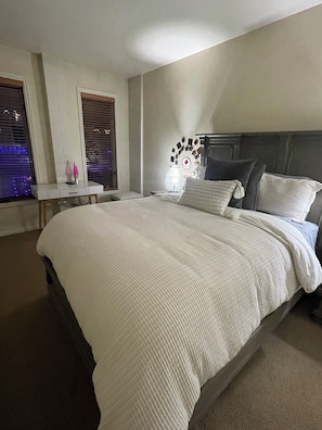 A bedroom with a large bed, bedside tables, a nightstand, and a decorative wall piece. - Ski Condo on Main Street Park City - 1BR/1BA. Walk to Lifts & Dining (Park City)