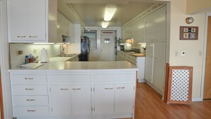 A spacious kitchen with white cabinetry, a central island, and a small refrigerator.