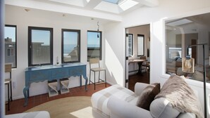 Una sala de estar moderna con un sofá, un aparador azul y un amplio ventanal con vistas al mar.