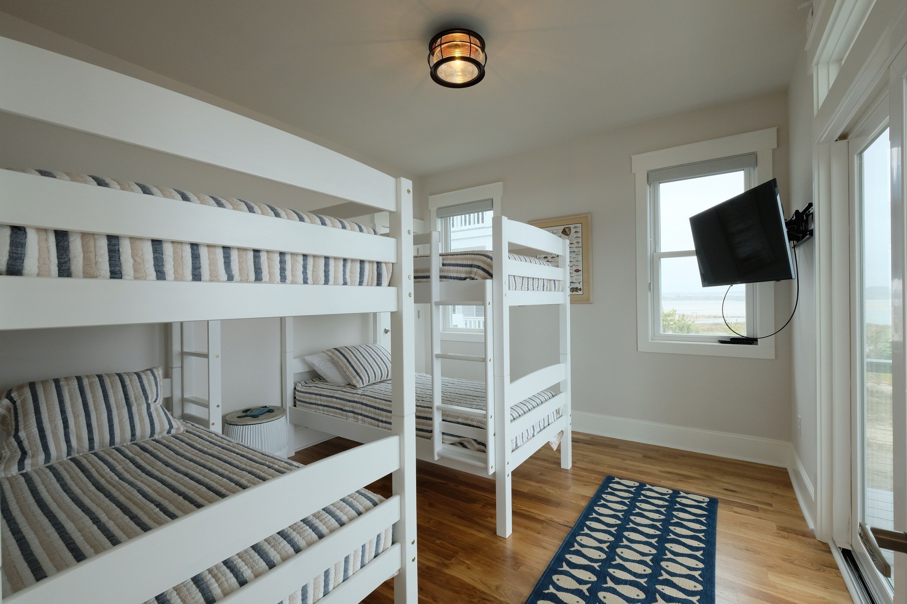 A child’s room with bunk beds, a television, and a window.
