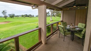 A covered outdoor seating area with a view of a golf course.