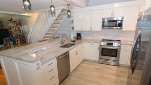 A modern kitchen with white cabinetry, a built-in oven, a microwave, and a stainless steel refrigerator.