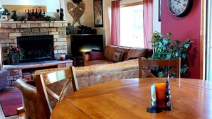 A cozy living room with a fireplace, a dining table, and a large clock on the wall. - Magnificent Mountain Side~Recently Remodeled (Frisco)