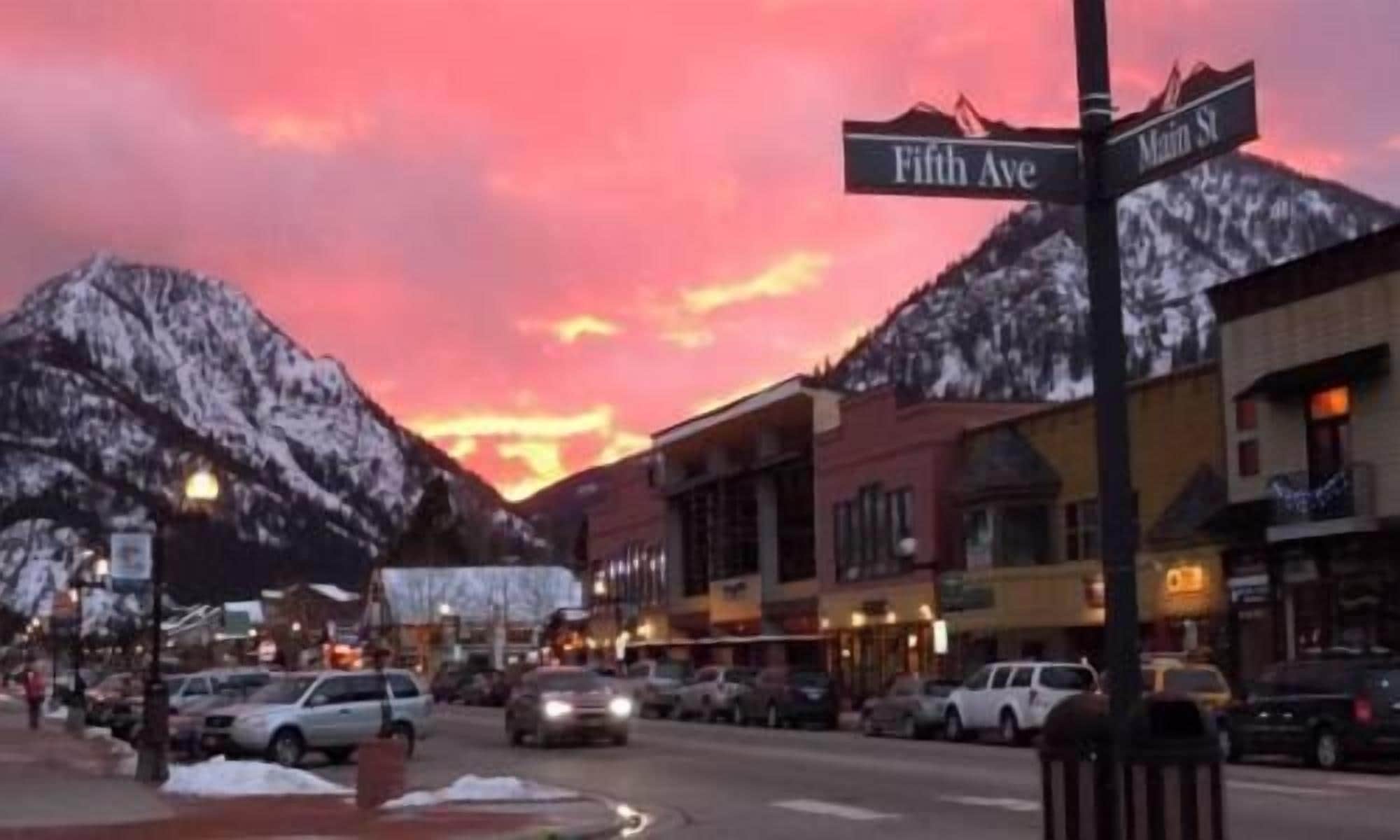A street view with a mountain backdrop, street signs for Fifth Ave and Main St, and buildings with storefronts.