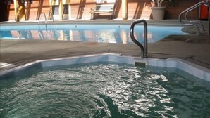 An indoor swimming pool with clear water, a metal ladder, and a wooden deck area with chairs and potted plants. - Magnificent Mountain Side~Recently Remodeled (Frisco)