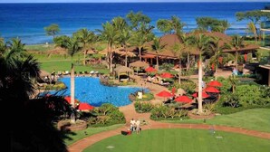 Een resort met een zwembad, palmbomen en uitzicht op de oceaan.