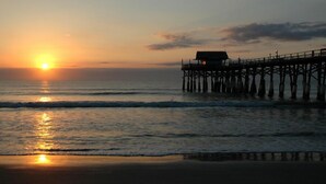 A pier extending into calm waters at sunset. - Premier Condo at Cocoa Beach Towers: top floor, corner closest to Ocean + Pier (Cocoa Beach)