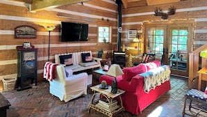 Interior de una cabaña de madera con chimenea, televisor y un rincón de estar acogedor.