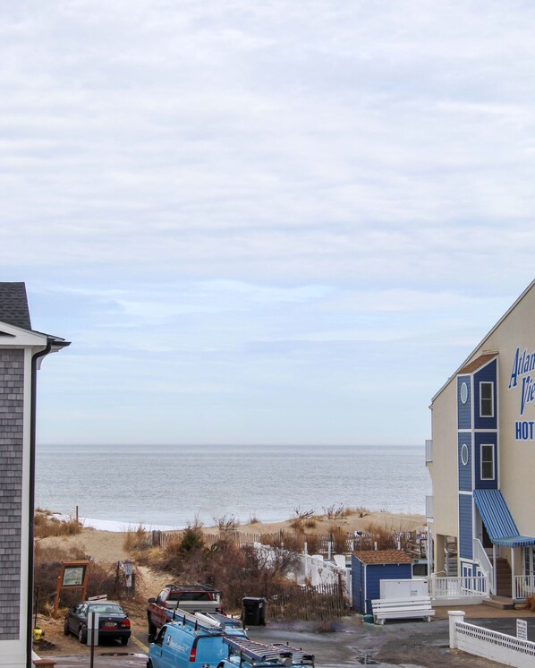 A view of a beachside hotel with a parking area in the foreground and a clear view of the ocean in the background. - Dewey Beach Townhouse Ocean Block (Dewey Beach)