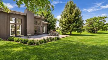 Une maison moderne à deux étages, dotée d’un patio et d’un espace extérieur aménagé pour s’asseoir.