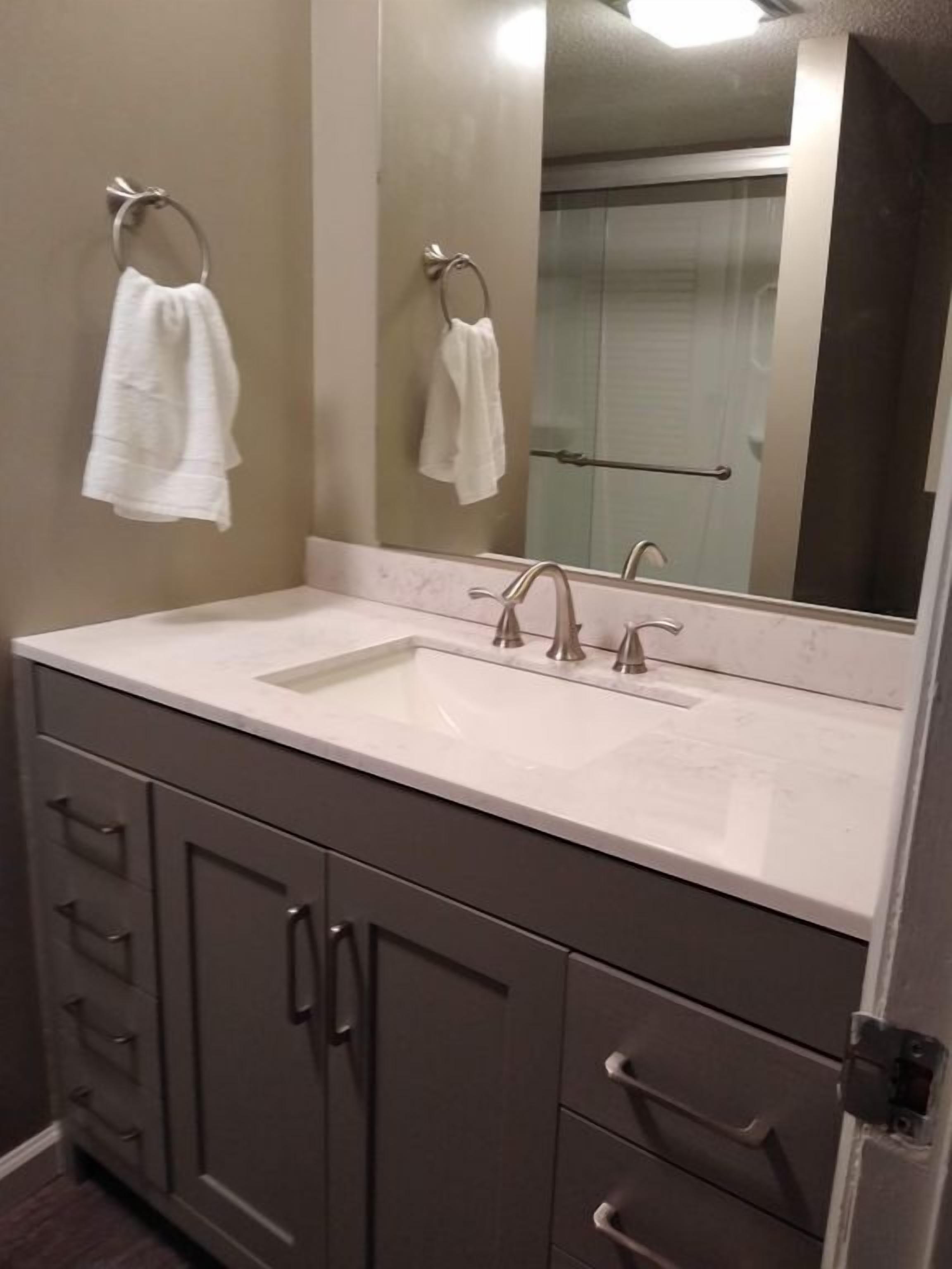 A bathroom with a double sink, a large mirror, and a towel rack.
