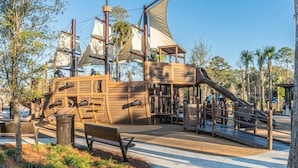 A pirate-themed play structure with slides and climbing areas, surrounded by trees and benches. - SOUTH FOREST BEACH. Coligny, pool. walk to beach. updated. sleep 8. 
SURF COURT (Hilton Head Island)