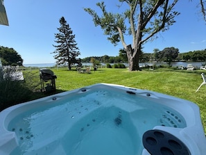 Uma banheira de hidromassagem em um quintal com vista para um lago e árvores.