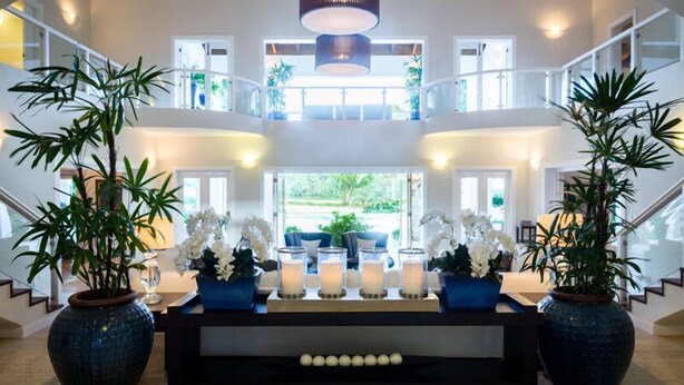 A spacious lobby with a central seating area, large potted plants, and a staircase leading to upper floors. - WALKING DISTANCE TO THE BEACH (Casa de Campo)