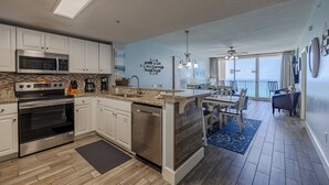A modern kitchen with built-in appliances, a dining area with a view, and a spacious living area with a ceiling fan.