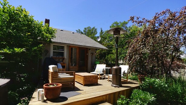 Een houten terras met tuinmeubilair, een terrasverwarmer en een tuin met diverse planten.
