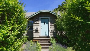Een klein, laag huis met een blauwe deur en een klein terras.