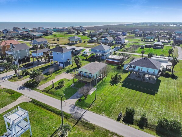 A residential area with houses, roads, and a beach in the background.