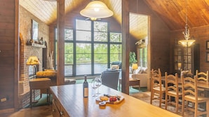 Un intérieur rustique en bois, avec une grande table à manger, des chaises et une cheminée.
