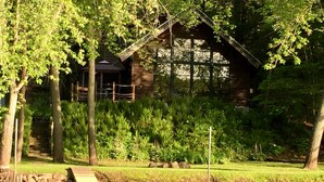 A wooden cabin with a dock extending into a calm lake, surrounded by lush greenery and trees. - Beautiful Cabin on Scenic WI River/Lake Wisconsin. Close to WI Dells and Madison (Poynette)