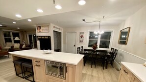 A modern kitchen with a central island, dining area, and a ski patrol sign on the wall. - Luxury Heart Of Old Town 3-Bdrm+ HOT TUB Walk To Skiing Chairlift Dining Main St (Park City)