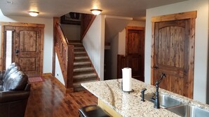 Eine Küche mit einer Granitabdeckung, einer Spüle aus Edelstahl, Holztüren und einer Treppe.