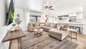Ein modernes Wohnzimmer mit einem Ecksofa, einem Couchtisch und einem an der Wand befestigten Fernseher.