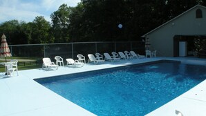 A rectangular swimming pool with white lounge chairs arranged along the edge. - Pet Friendly Condo Overlooking Pool And Tennis Court.  (Monticello)