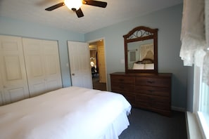 Un dormitorio con cama, cómoda, espejo y ventilador de techo.