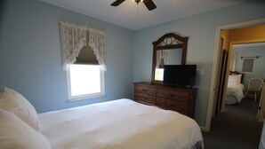 A bedroom with a bed, dresser, television, and a window with a curtain. - Pet Friendly Condo Overlooking Pool And Tennis Court.  (Monticello)