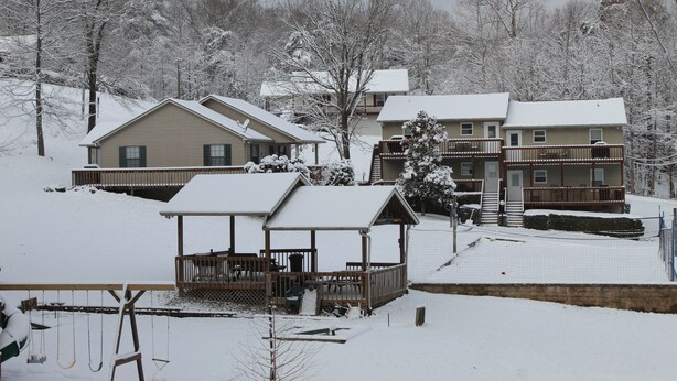 A snow-covered residential area with houses, a wooden deck, and a swing set. - Pet Friendly Condo Overlooking Pool And Tennis Court.  (Monticello)