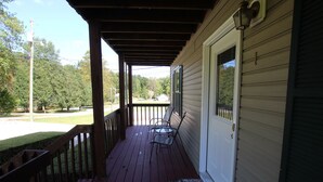 A covered porch with a wooden railing, a bench, and a door with a window. - Pet Friendly Condo Overlooking Pool And Tennis Court.  (Monticello)